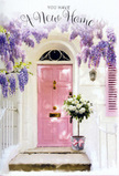 This image could easily belong to a newly claimed doorway in South Hackney, where creativity and home comfort blend seamlessly. At its heart is a pale pink front door, painted in a smooth, matt finish that lends it a calm, contemporary character while still feeling warm and inviting. The surrounding wall is whitewashed and lightly textured, offering a clean backdrop that lets the colour of the door and the surrounding flowers shine. Above, generous strands of wisteria hang in loose, lavender masses, their blossoms tumbling down in clusters that partially veil the top of the doorway, like a soft floral curtain. The purple tones of the wisteria create a delicate contrast against the white masonry and pick up the blush of the door, echoing the sort of thoughtful styling you might see on side streets leading to London Fields or around Well Street. On the doorstep, a grey metal bucket holds a beautifully composed bouquet of white and cream roses. The blooms are full and rounded, gathered closely together so they appear plush and abundant, with their velvety petals catching the late-day light. Slim stems of muted green foliage thread between the roses, softening the edges and adding gentle texture. A pink ribbon, tied neatly around the bucket's base, completes the arrangement with a hint of playful elegance, tying together the pink of the door and the lavender of the wisteria above. The atmosphere is serene, touched with anticipation, as if this display has just been delivered to celebrate a move into a new home off Mare Street or near the Regent's Canal, offering comfort, joy, and a tender sense of welcome each time the key turns in the lock.